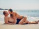 une couple s'embrassant sur la plage renforcée par un palmier nain