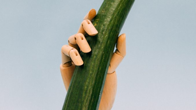 une main de figurine tennante un comcombre en imitant jelqing